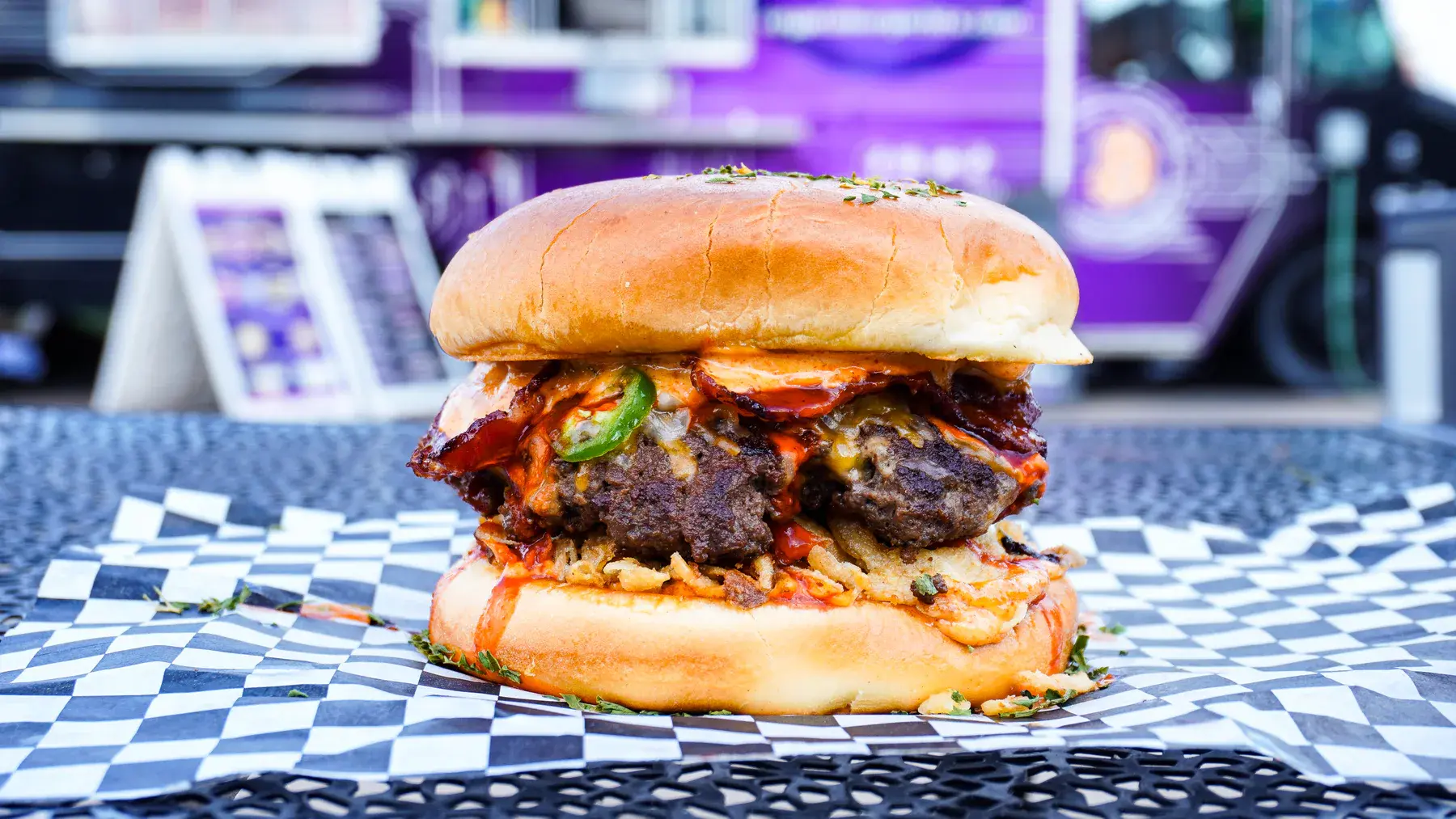 Bull Run Burger with serrano peppers, halal bacon, fried onions, and spicy FOMO sauce